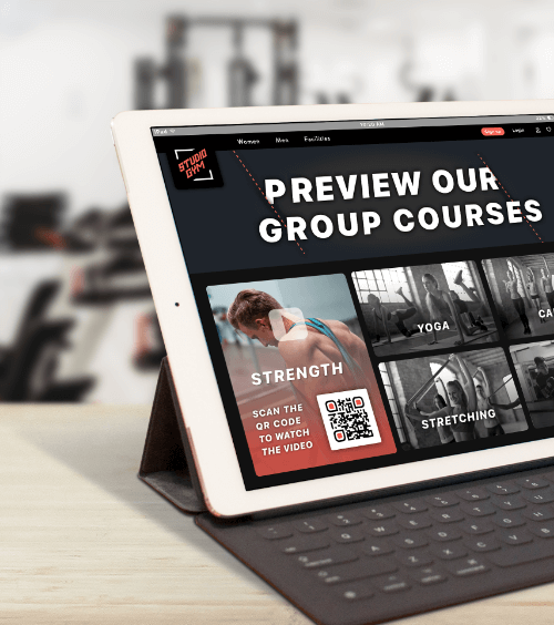 Um tablet na academia que divulga cursos em grupo com um QR Code que incentiva usuários a ver uma playlist de vídeos dos cursos.